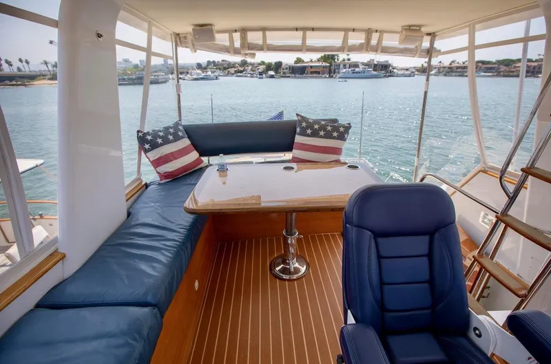 Following Sea Yacht Photos Pics Interior of a 1965 Bertram 56 yacht with blue seating and American flag pillows.