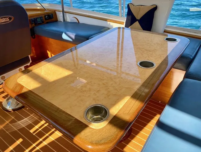 Following Sea Yacht Photos Pics Luxurious wooden table on a 1965 Bertram 56 yacht, with ocean view.