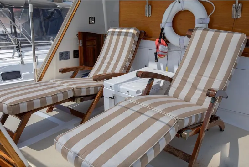 Following Sea Yacht Photos Pics Striped lounge chairs on a 1965 Bertram 56 yacht deck with life preserver.