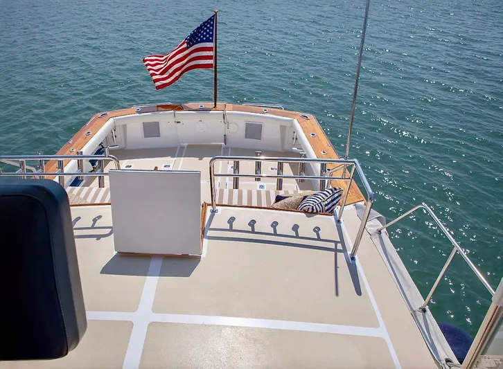 Following Sea Yacht Photos Pics 1965 Bertram 56 yacht deck with American flag, overlooking calm ocean waters.