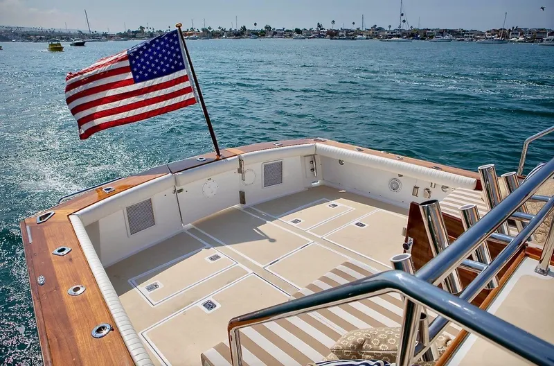 Following Sea Yacht Photos Pics Vintage 1965 Bertram 56 yacht deck with American flag, overlooking serene waters.