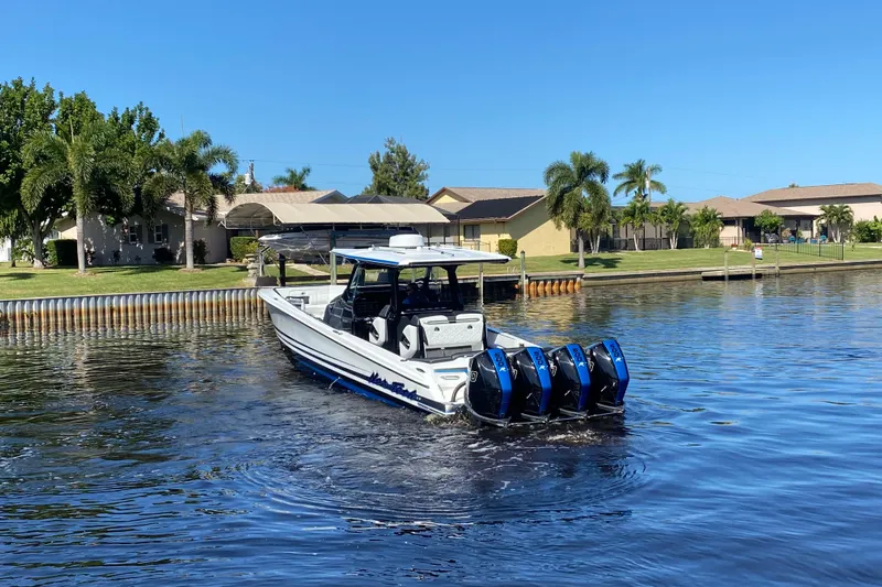  Yacht Photos Pics 2024 Nor-Tech 400 Supersport boat cruising on a sunny waterfront with palm trees.