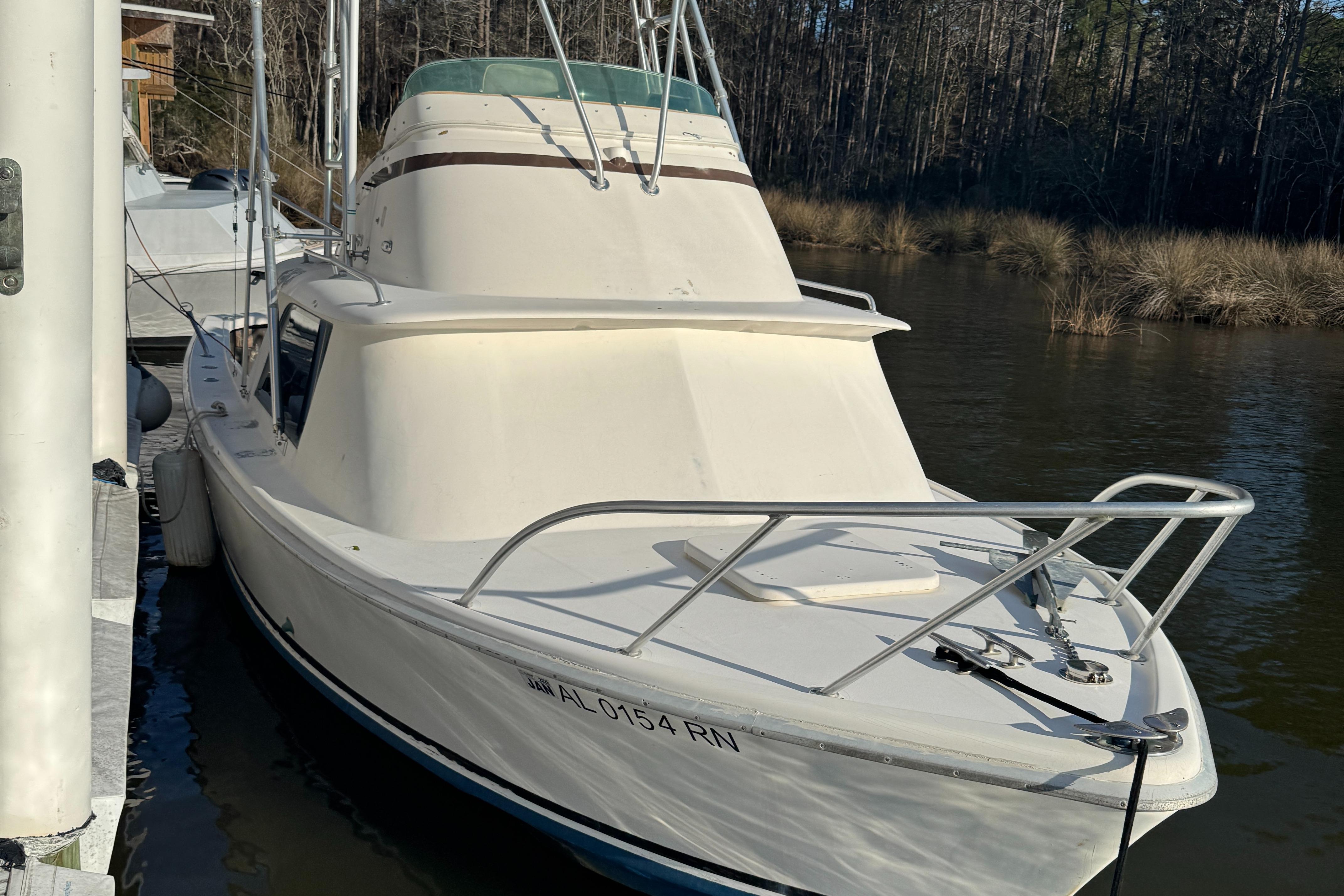 1974 Bertram 31 Flybridge boat docked on a calm river.