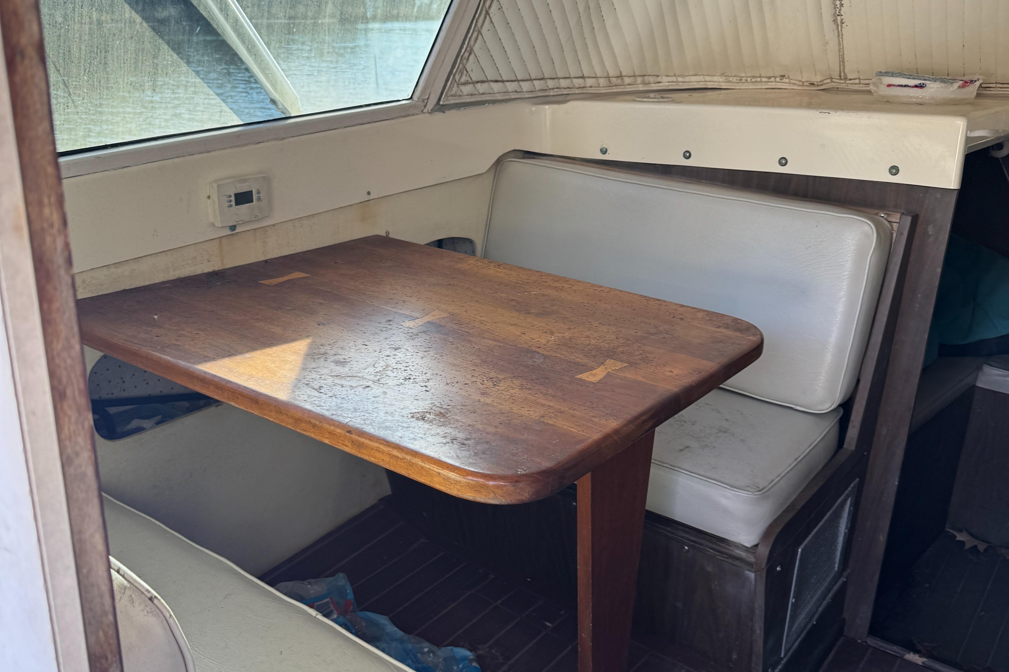 1974 Bertram 31 Flybridge interior with wooden table and cushioned seating.