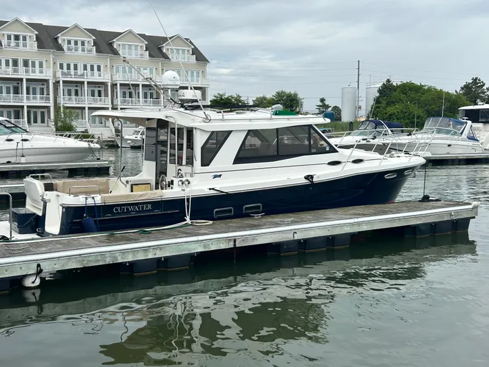  Yacht Photos Pics 2014 Cutwater C-30 Sedan docked at a marina with waterfront buildings in the background.
