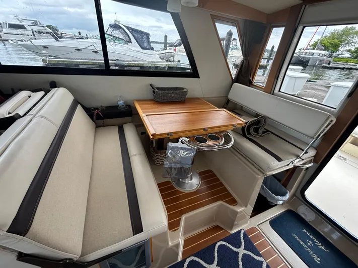  Yacht Photos Pics Interior of 2014 Cutwater C-30 Sedan with seating and wooden table, docked at marina.
