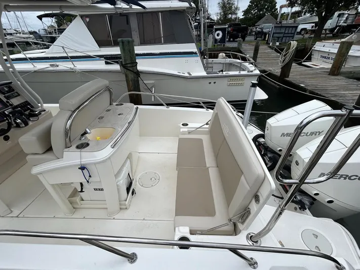  Yacht Photos Pics 2022 Boston Whaler 27 Dauntless boat interior with seating and Mercury engines at a marina.