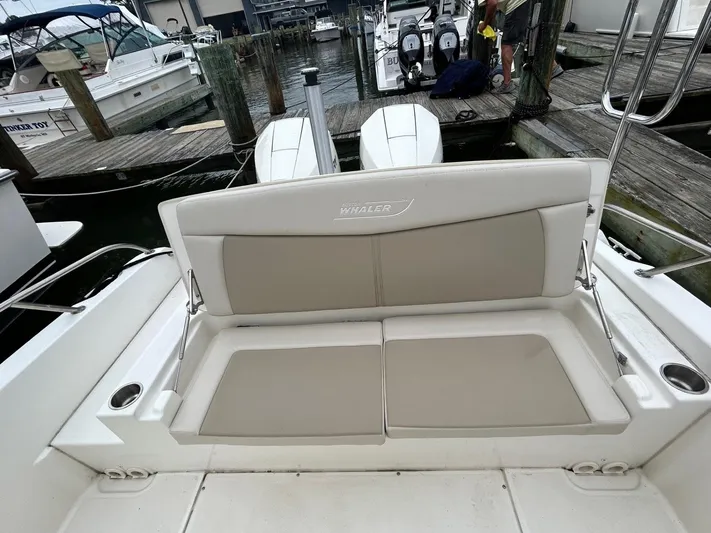  Yacht Photos Pics 2022 Boston Whaler 27 Dauntless boat with cushioned seating at a marina dock.