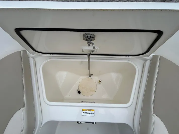  Yacht Photos Pics 2022 Boston Whaler 27 Dauntless boat storage compartment with open lid and faucet.