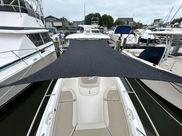  Yacht Photos Pics 2022 Boston Whaler 27 Dauntless with sunshade, docked among other boats.