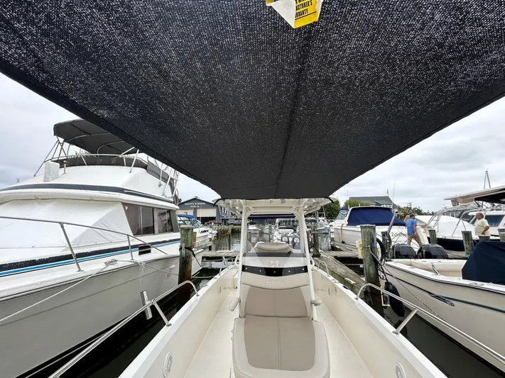  Yacht Photos Pics 2022 Boston Whaler 27 Dauntless boat docked, featuring spacious seating and overhead canopy.
