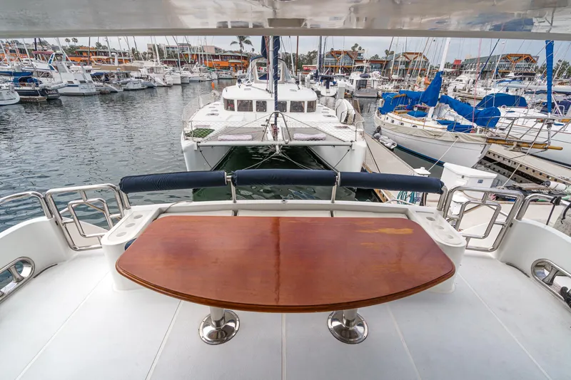 Dancing Lady Yacht Photos Pics 1999 Horizon 70 Motor Yacht deck with wooden table, overlooking marina with various boats.