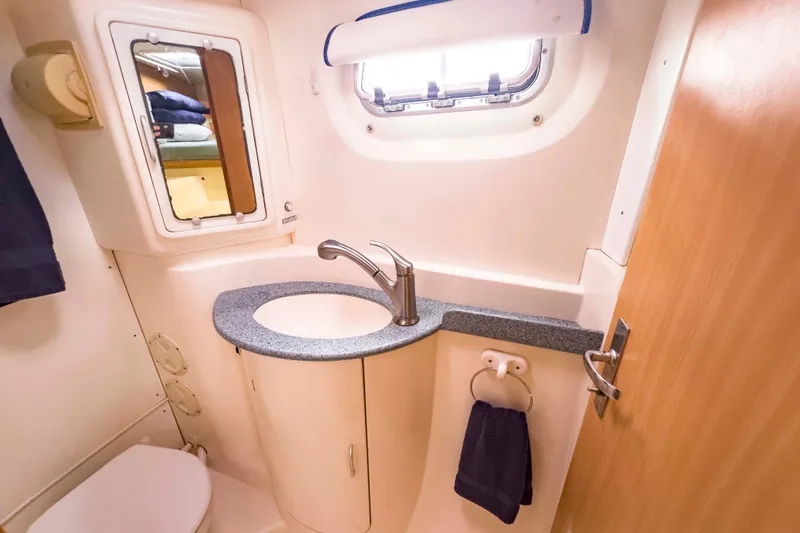 &Eacute;toile De Mer Yacht Photos Pics Compact bathroom in a 2002 Leopard 42 yacht, featuring sink, mirror, and porthole window.