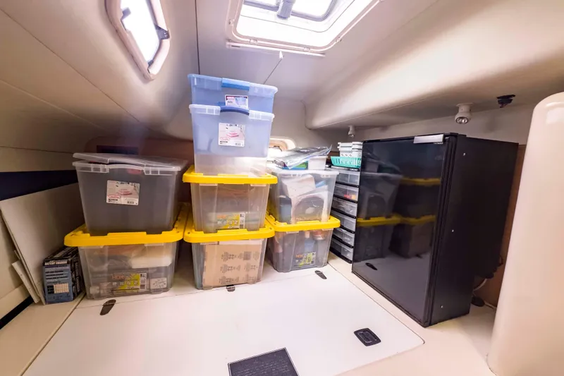 &Eacute;toile De Mer Yacht Photos Pics Storage area in a 2002 Leopard 42 yacht with organized plastic bins and a compact fridge.