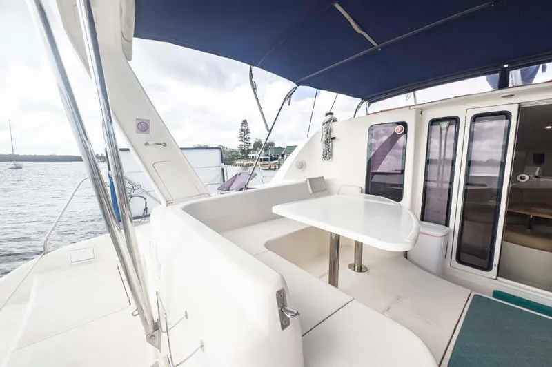 &Eacute;toile De Mer Yacht Photos Pics Spacious deck of 2002 Leopard 42 catamaran with seating and table, docked by the water.