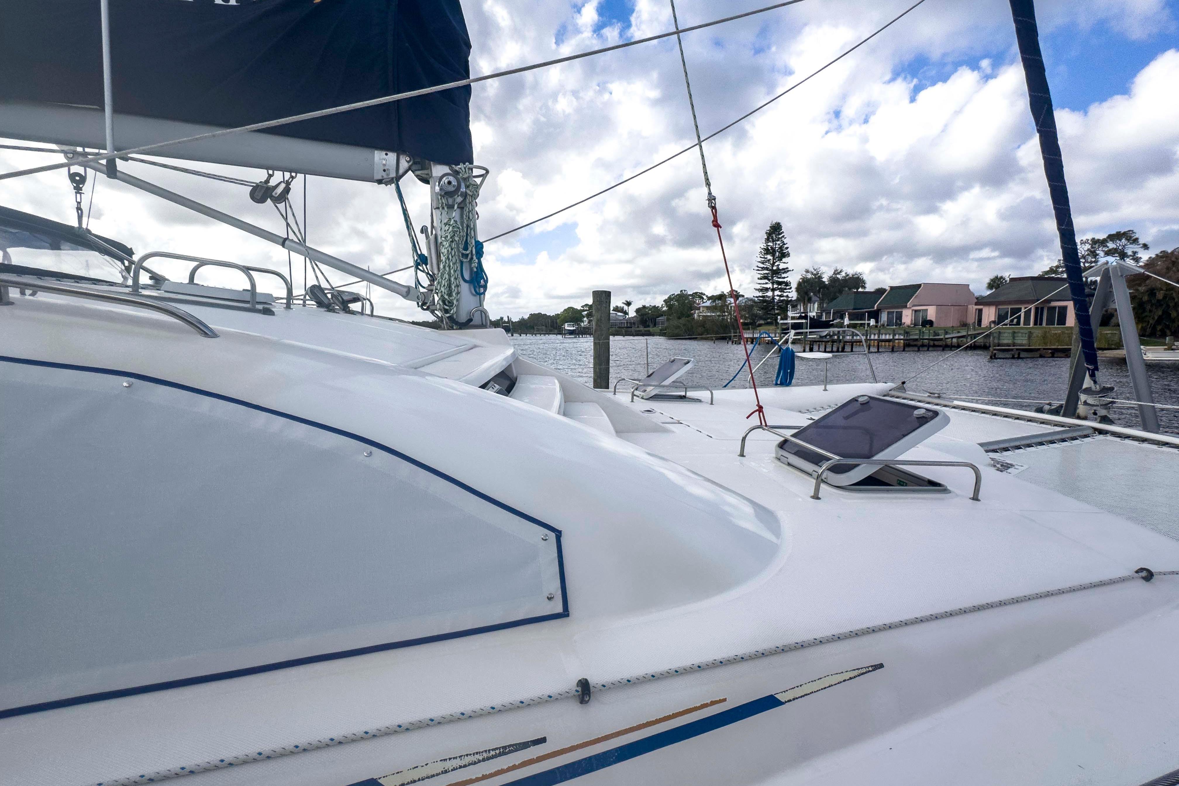 2002 Leopard 42 catamaran docked by a scenic waterfront with cloudy skies.