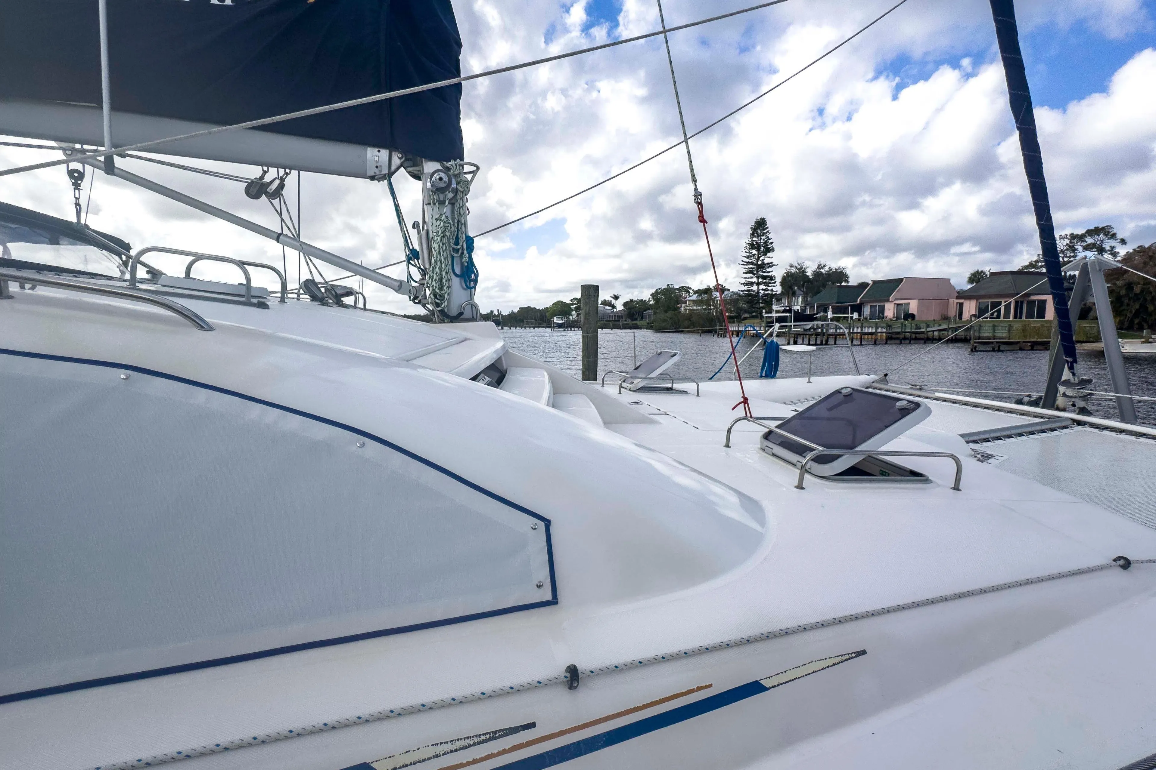 2002 Leopard 42 catamaran docked by a scenic waterfront with cloudy skies.