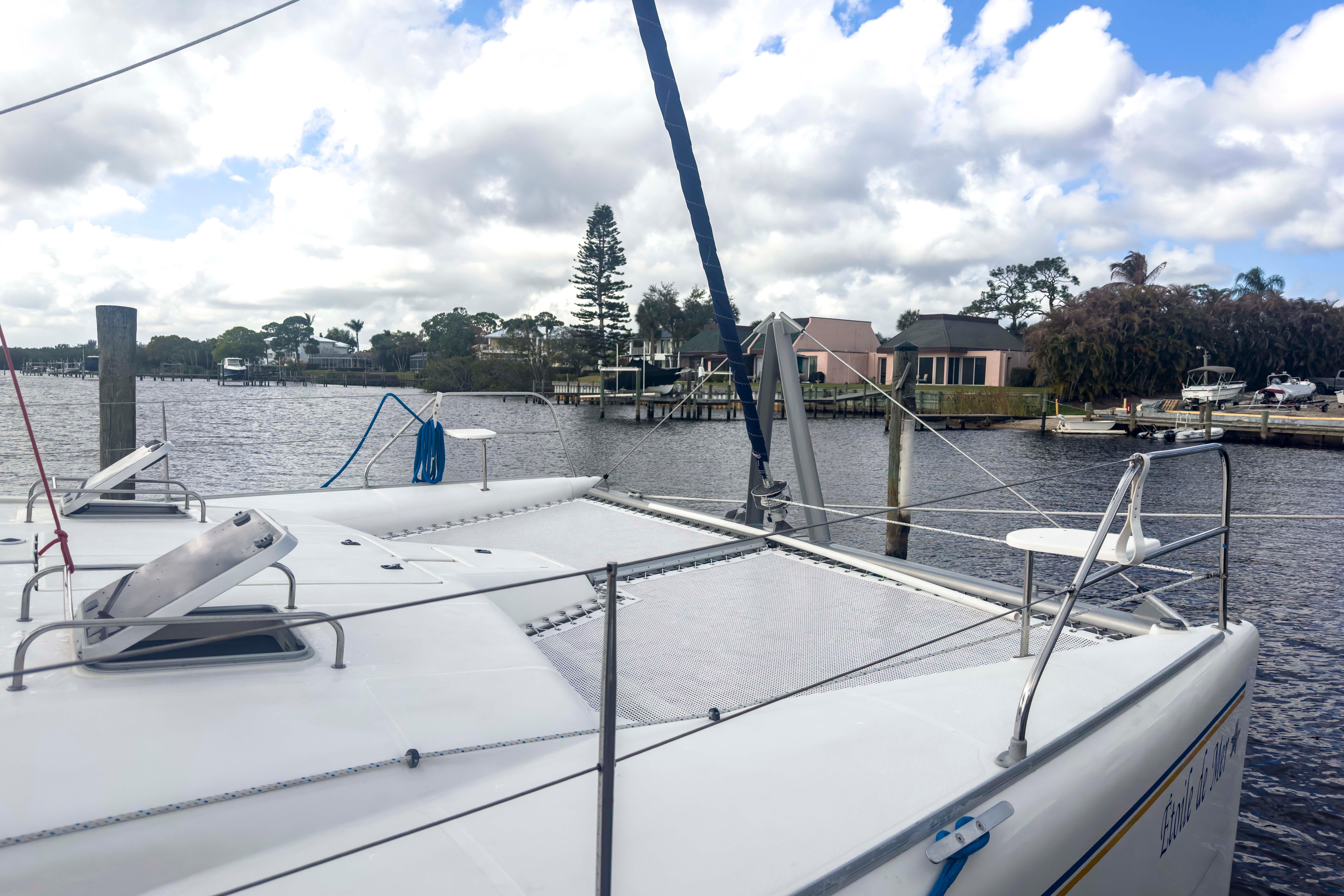 Catamaran Leopard 42, 2002 model, docked by a scenic waterfront with cloudy skies.