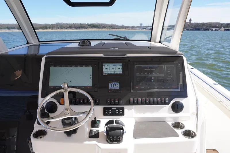  Yacht Photos Pics 2019 Pursuit S 408 Sport boat dashboard with navigation screens and steering wheel on open water.