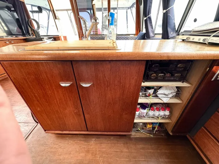  Yacht Photos Pics 1988 Bayliner 4550 Pilothouse interior kitchen with wooden cabinets and open shelves.