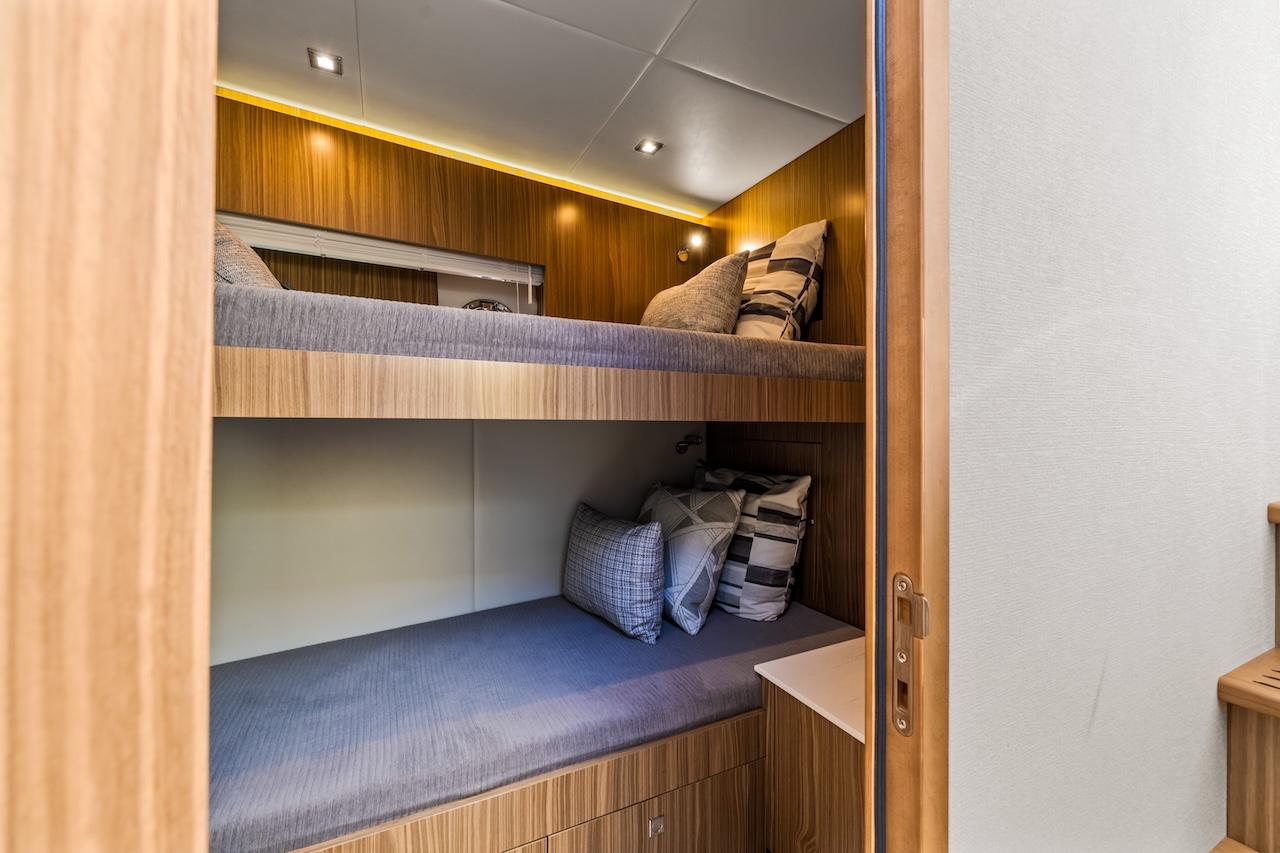 2024 Cruisers Yachts 50 Cantius cabin with cozy bunk beds and modern lighting.