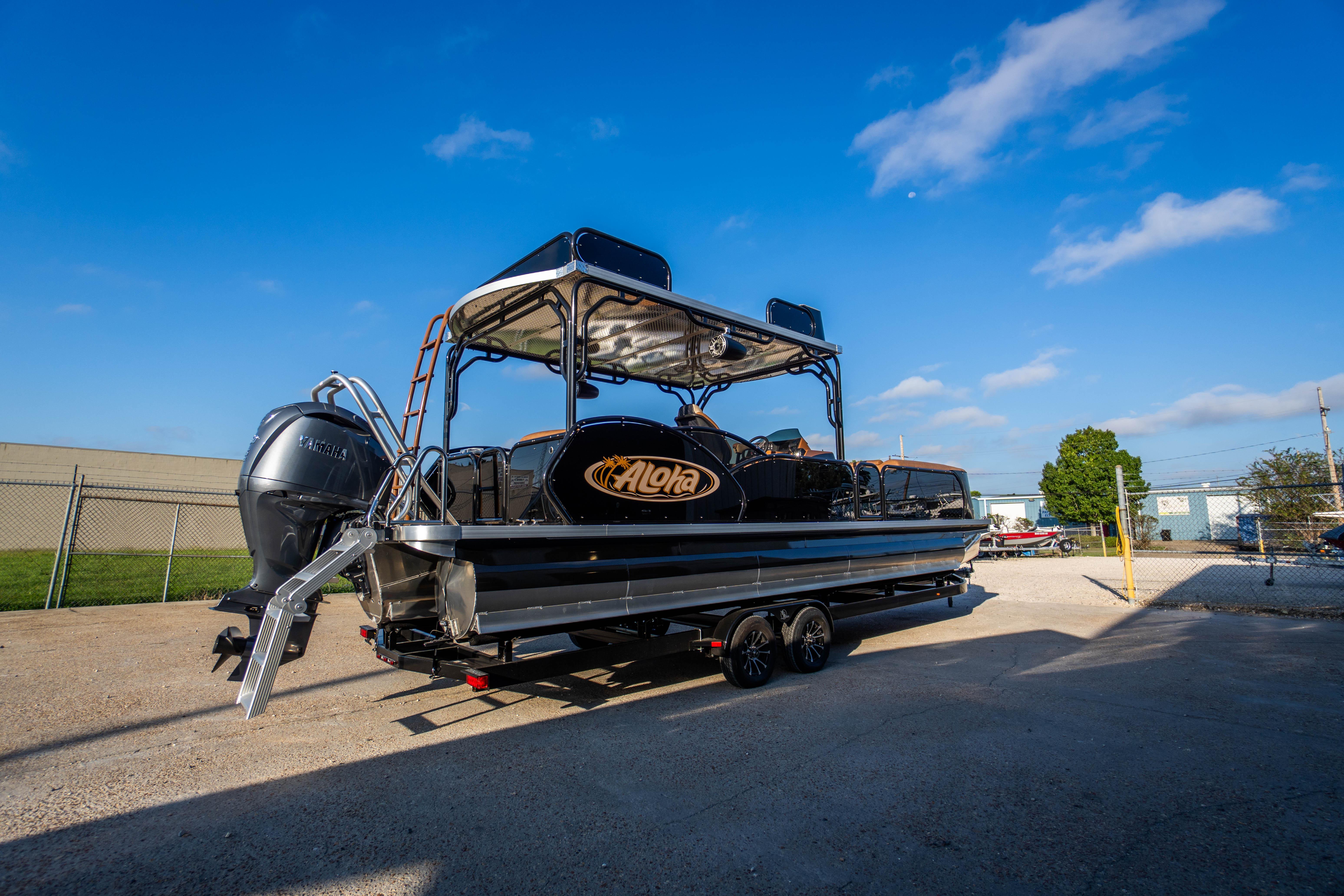 2026 Aloha Paradise 300 Sundeck boat on trailer under clear blue sky.
