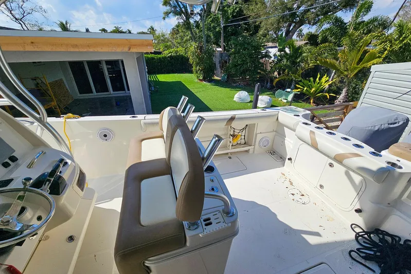 Buddy Yacht Photos Pics 2013 Sailfish 290 CC boat interior with seating, steering wheel, and lush backyard view.