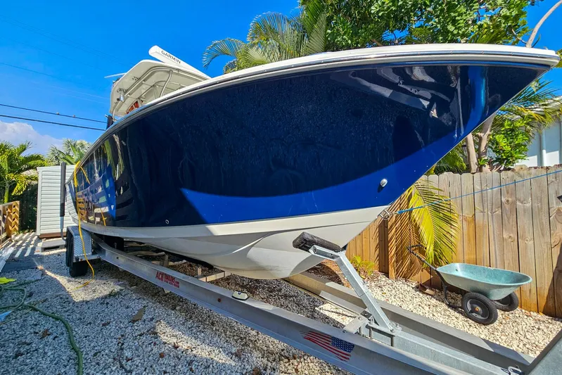 Buddy Yacht Photos Pics 2013 Sailfish 290 CC boat on trailer, blue hull, sunny day, palm trees in background.
