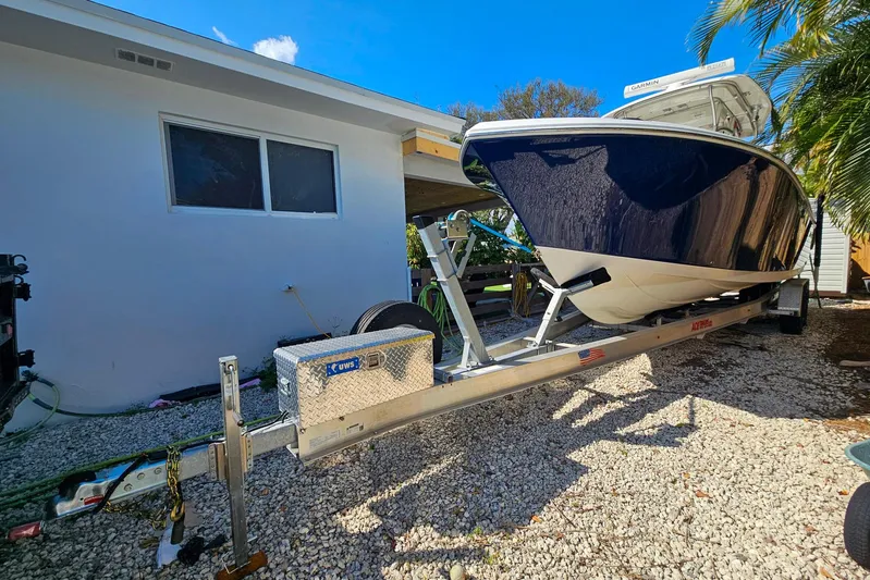 Buddy Yacht Photos Pics 2013 Sailfish 290 CC boat on trailer beside a house, under clear blue sky.