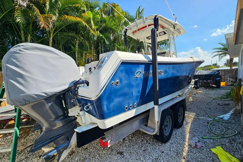 Buddy Yacht Photos Pics 2013 Sailfish 290 CC boat on trailer, parked outdoors with palm trees in background.