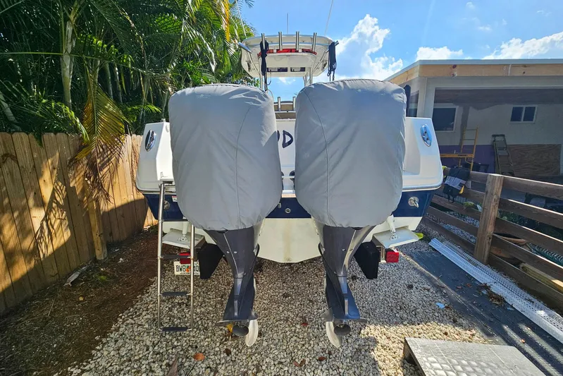 Buddy Yacht Photos Pics 2013 Sailfish 290 CC boat with covered outboard motors, parked on gravel.