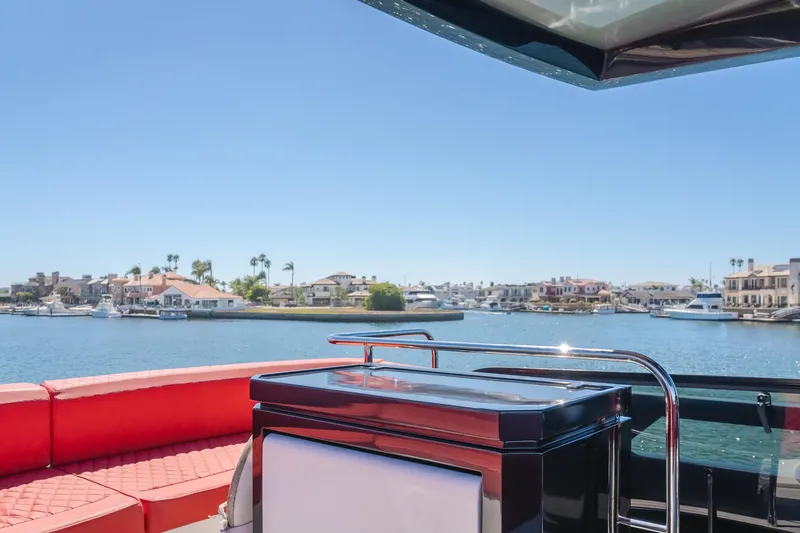 Saigon Yacht Photos Pics 2023 OKEAN 52 Fly yacht with red seating, overlooking waterfront homes and boats.