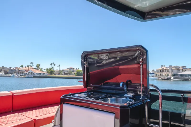 Saigon Yacht Photos Pics 2023 OKEAN 52 Fly yacht with outdoor sink and red seating, coastal view.
