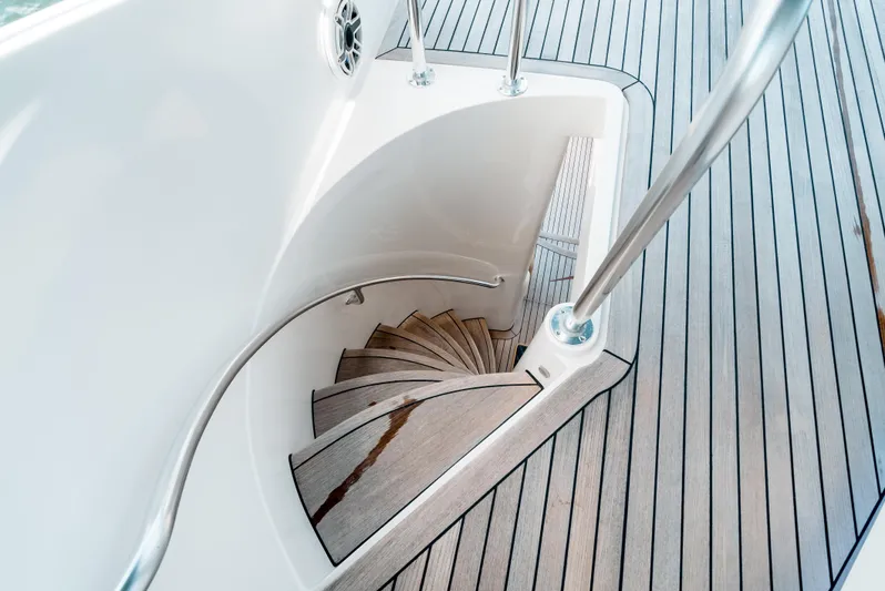 Relentless Yacht Photos Pics Curved staircase on 2006 Bertram Sportfish yacht with sleek wooden deck.