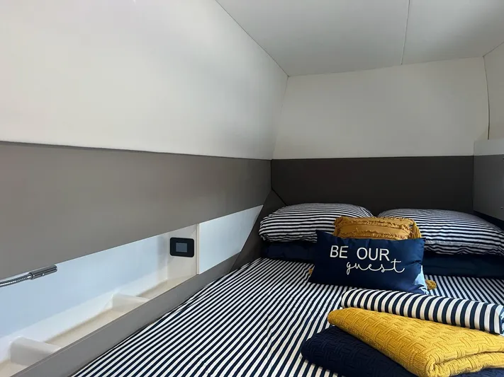 Encore Yacht Photos Pics Cozy cabin interior of 2020 Bali 4.1 yacht with striped bedding and decorative pillows.
