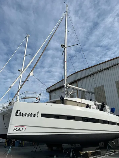 Encore Yacht Photos Pics 2020 Bali 4.1 catamaran docked near a warehouse under a cloudy sky.