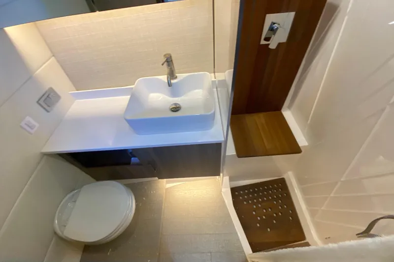  Yacht Photos Pics 2021 Regal 38 SAV bathroom with modern sink, toilet, and wooden shower seat.