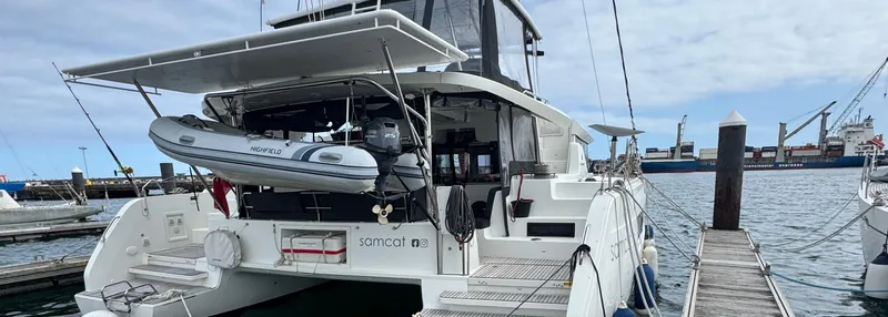 Samcat Yacht Photos Pics 2020 Lagoon 46 catamaran docked at marina with inflatable dinghy and clear sky.