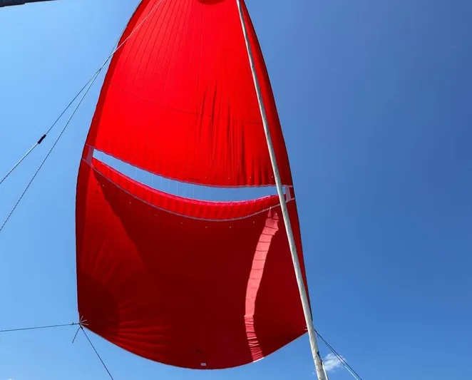 Samcat Yacht Photos Pics Red sail on Lagoon 46 catamaran, 2020 model, against clear blue sky.