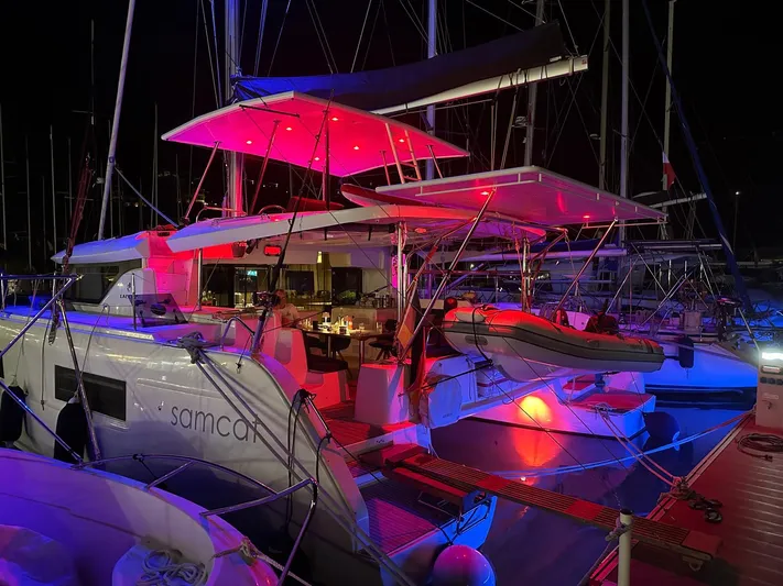 Samcat Yacht Photos Pics 2020 Lagoon 46 catamaran illuminated with vibrant red and blue lights at night.