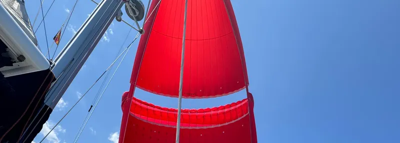 Samcat Yacht Photos Pics Red sail on Lagoon 46 catamaran, 2020 model, against clear blue sky.