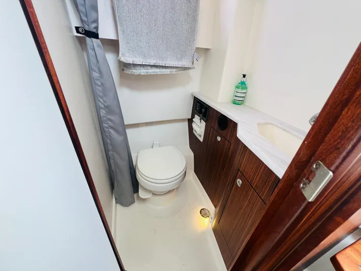  Yacht Photos Pics 2022 Pursuit S 358 Sport boat bathroom with toilet, sink, and wooden cabinetry.