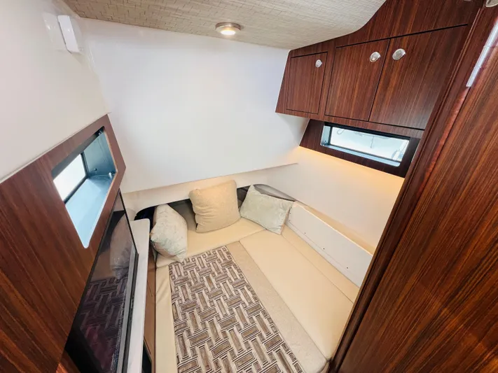  Yacht Photos Pics 2022 Pursuit S 358 Sport cabin interior with cozy seating and wooden cabinetry.