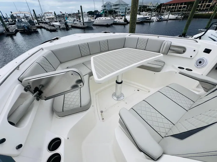  Yacht Photos Pics 2022 Pursuit S 358 Sport boat interior with elegant seating and table, docked at marina.