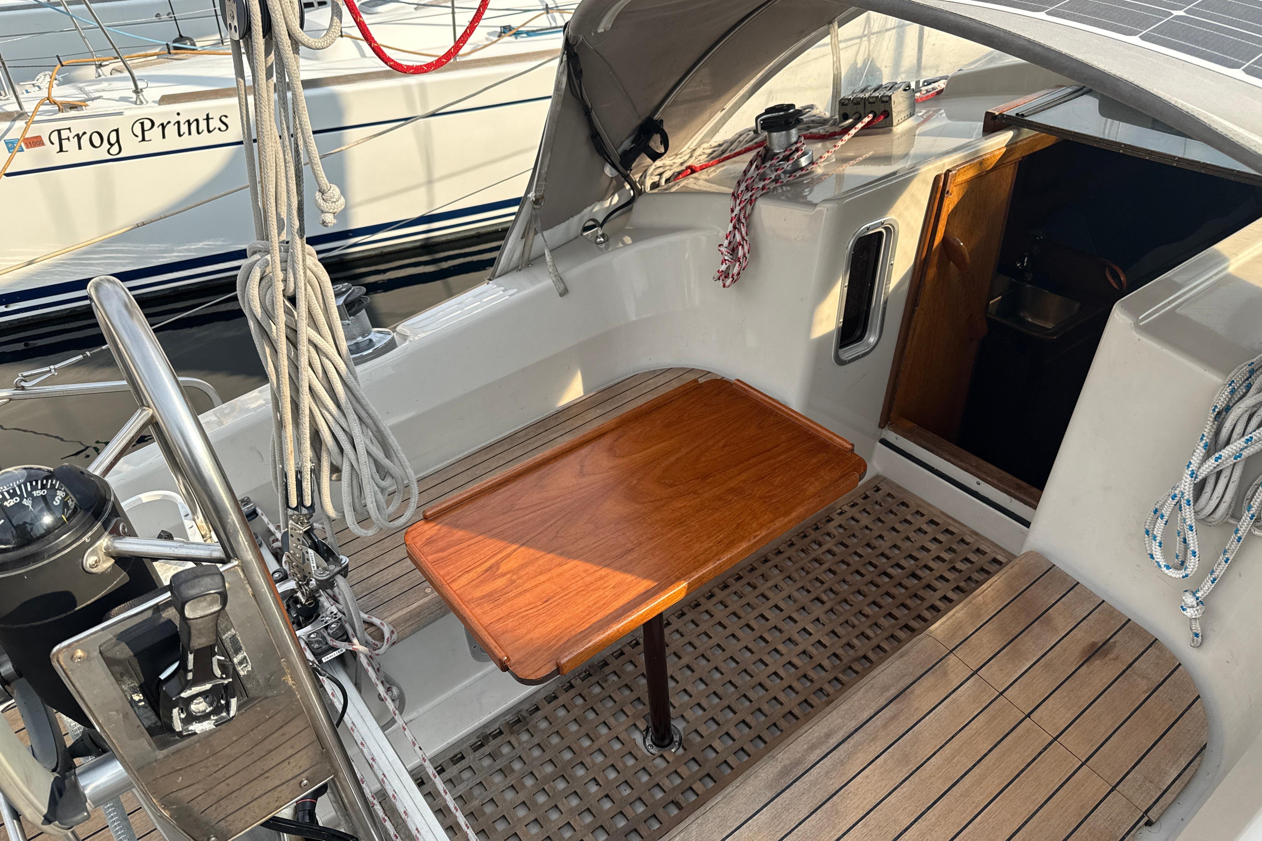 Cockpit of 1985 Dehler 372 sailboat with wooden table and nautical equipment.
