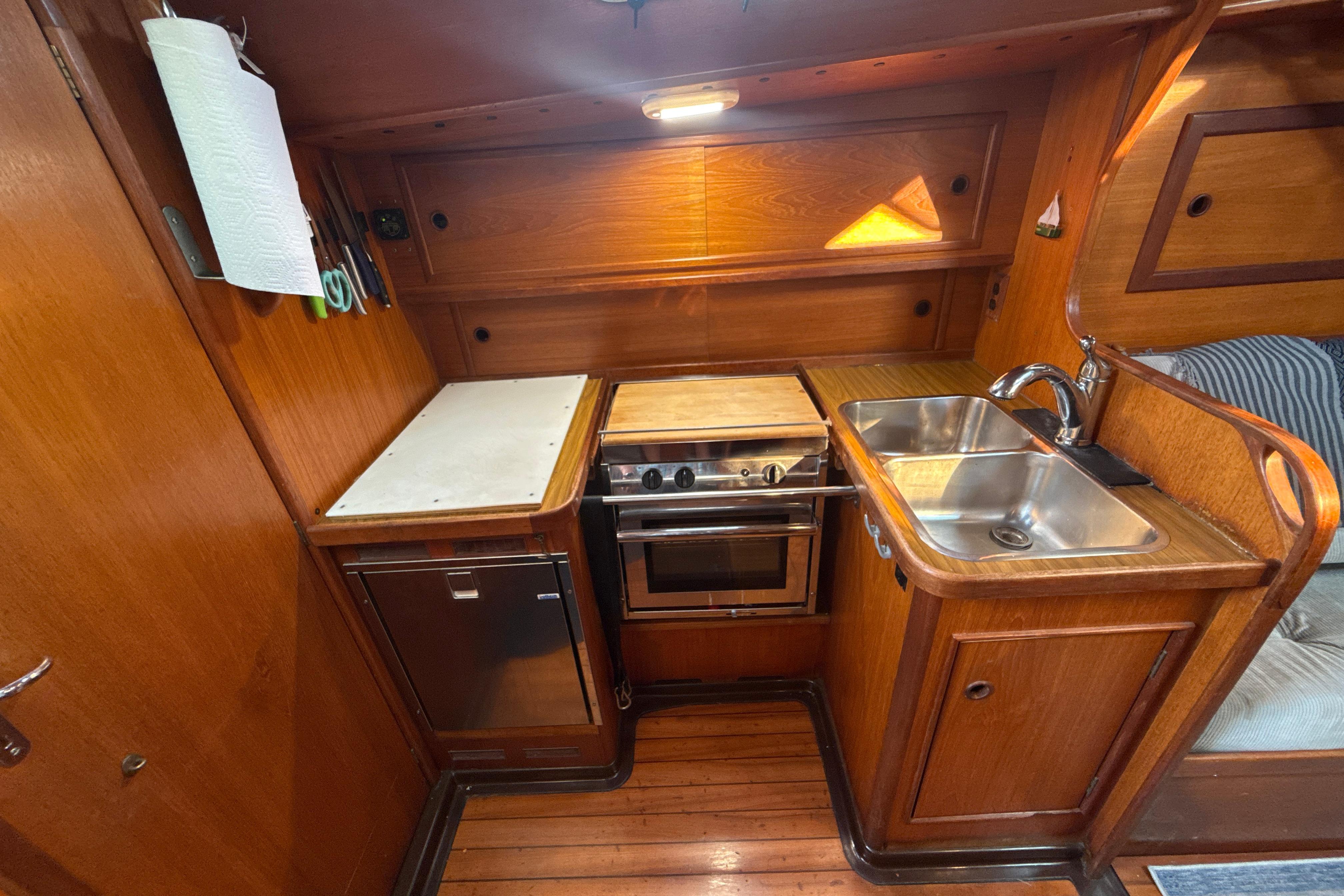 1985 Dehler 372 yacht kitchen with wooden cabinetry, stove, sink, and compact design.