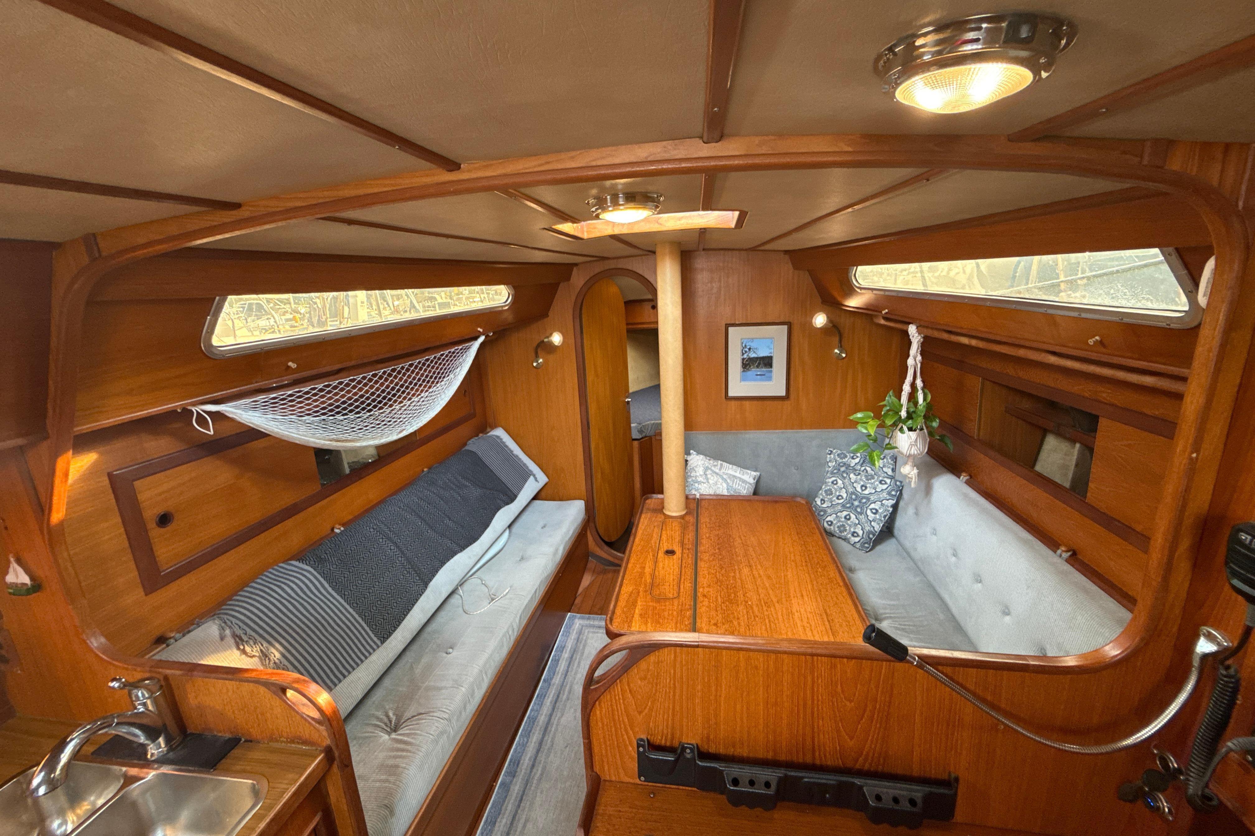 Interior of 1985 Dehler 372 sailboat with cozy wooden furnishings and seating area.