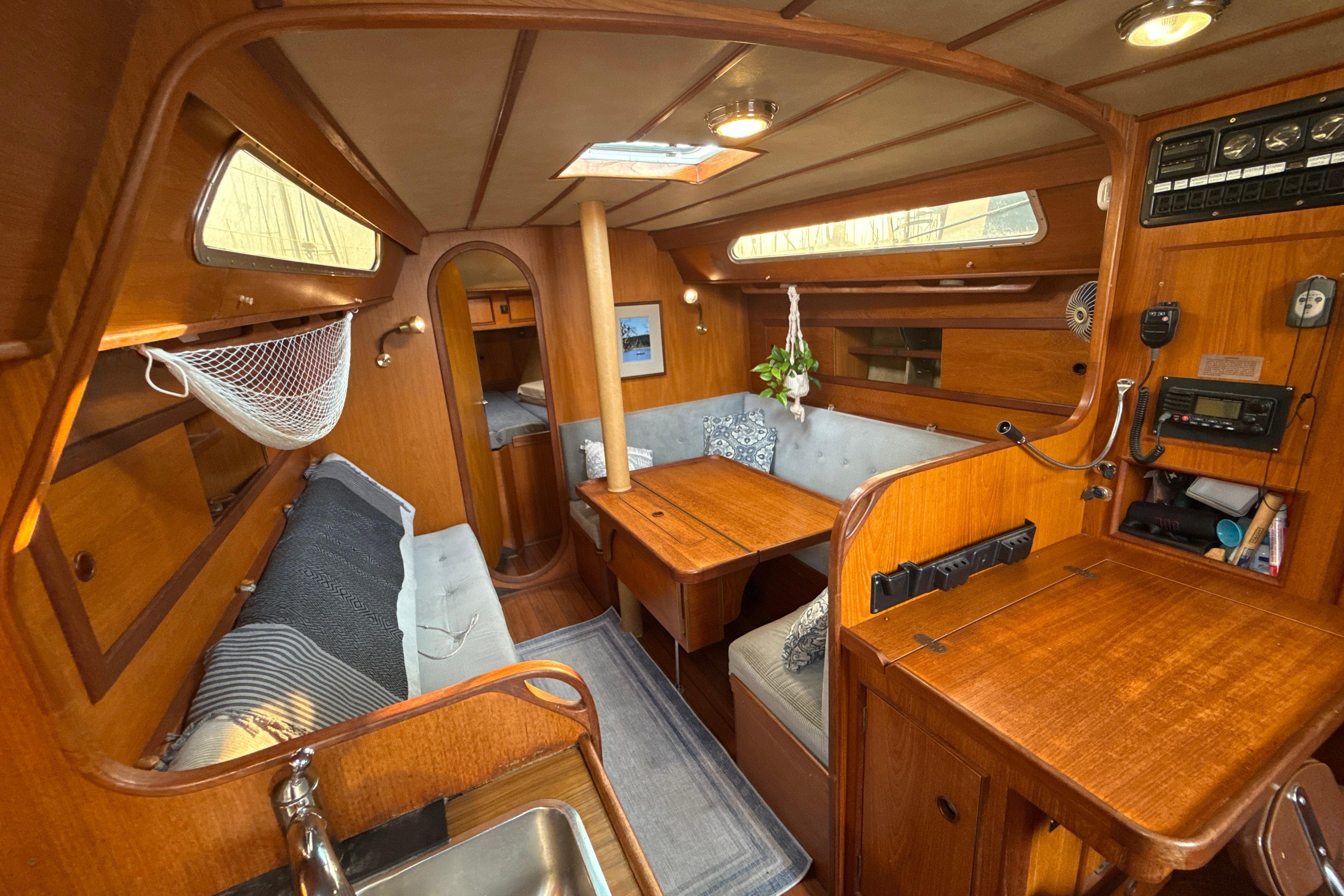 Interior of 1985 Dehler 372 sailboat with wooden furnishings and cozy seating area.