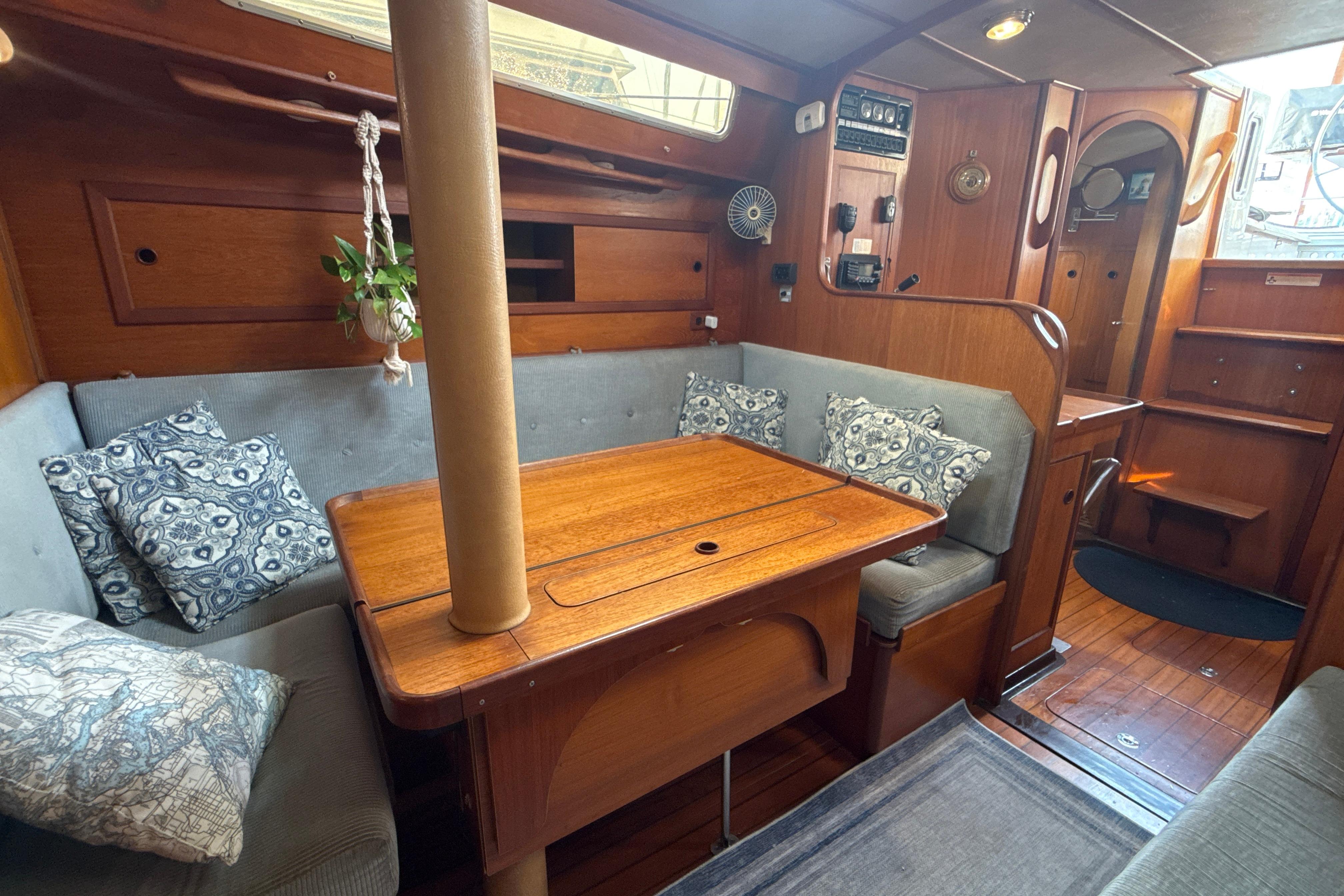 Interior of 1985 Dehler 372 sailboat with cozy seating and wooden table.