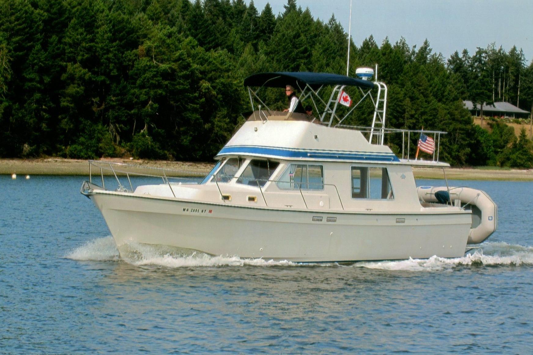 1986 Custom Lynnwood Flybridge Sedan cruising on a serene lake with forested shoreline.